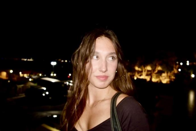 Picture of senior student Nettie James-Drost with long brown hair in front of a large city at night.