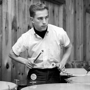 A black-and-white photo of Dr. Michael Bresler, M.D. playing timpani with the World Youth Symphony Orchestra during summer 1964.